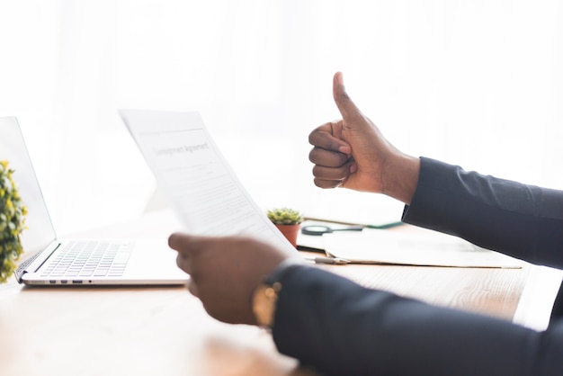 Hombre de negocios con papel gesticular pulgar arriba