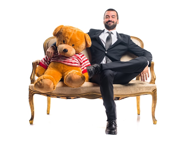 Hombre de negocios con peluche sentado en el sillón vintage