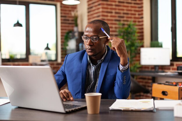 Hombre de negocios pensando en una solución innovadora y un proyecto de planificación en una computadora portátil. Emprendedor pensativo que intercambia ideas financieras para planificar la estrategia de marketing en la computadora para la puesta en marcha.