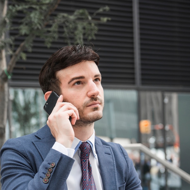 Hombre de negocios pensativo hablando en teléfono inteligente