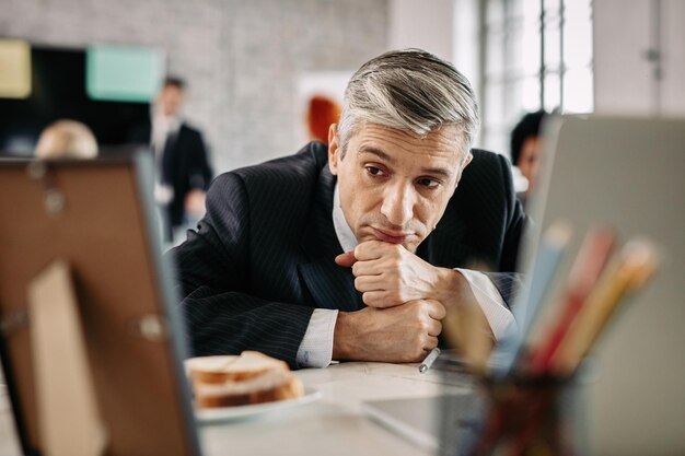 Un hombre de negocios pensativo que se siente cansado del trabajo y contempla mientras está sentado en el escritorio de la oficina