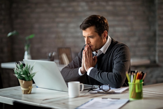 Foto gratuita hombre de negocios pensativo que trabaja en la oficina y se concentra en el correo electrónico que está leyendo en la computadora portátil