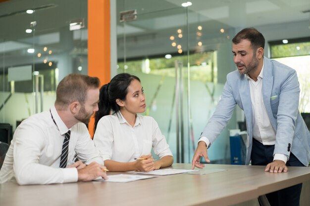 Hombre de negocios de pie y discutir problemas con colegas