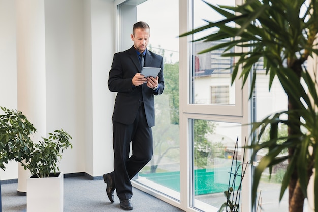 Foto gratuita hombre de negocios de pie en la oficina con la mesa