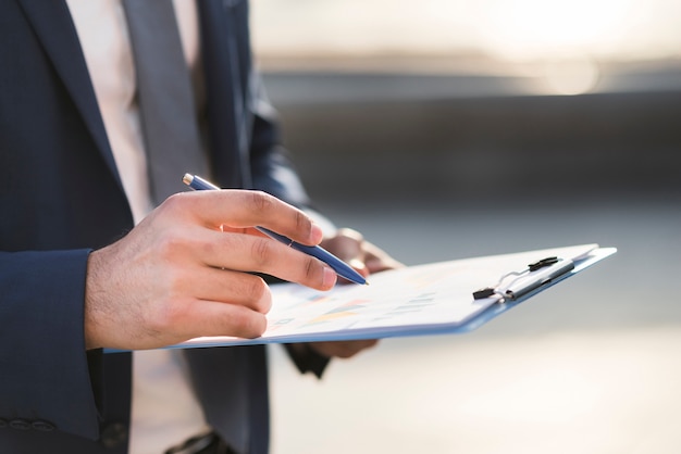 Hombre de negocios de primer plano comprobando portapapeles