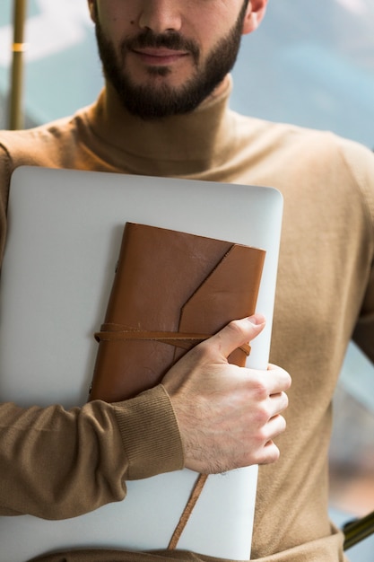 Hombre de negocios de primer plano con laptop y agenda