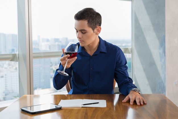 El hombre de negocios que beben el vino en restaurante después del trabajo