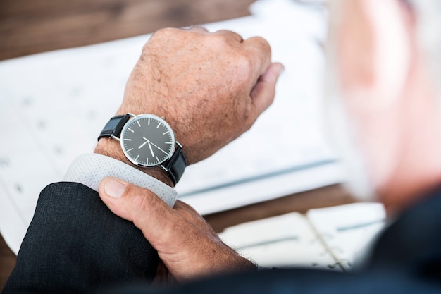 Hombre de negocios que controla tiempo en reloj de mano