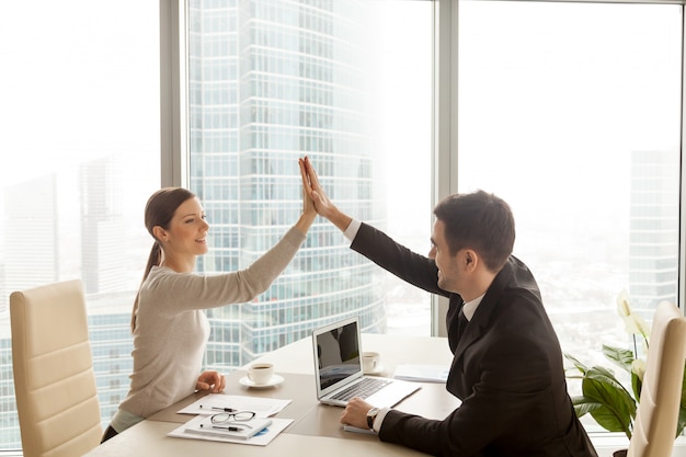 Foto gratuita hombre de negocios que da a empresaria el alto cinco en la oficina