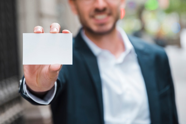 Hombre de negocios que muestra la tarjeta de visita blanca hacia la cámara