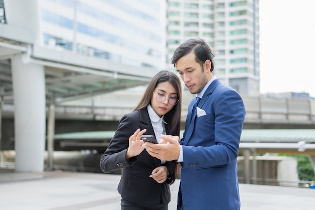 Hombre de negocios que muestra el teléfono móvil a colega fuera.