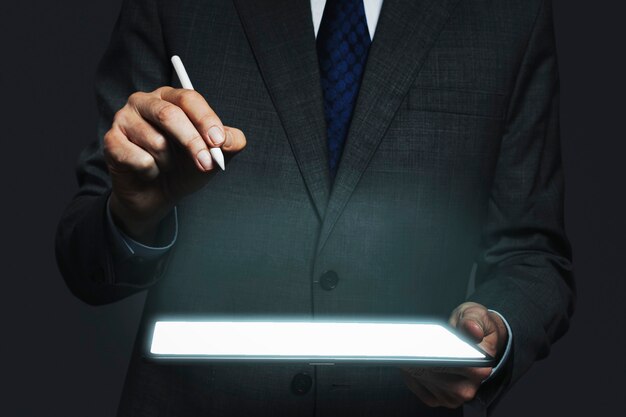 Hombre de negocios que presenta holograma invisible que se proyecta desde la tecnología avanzada de la tableta