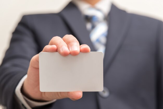 Hombre de negocios que sostiene la tarjeta en blanco blanca