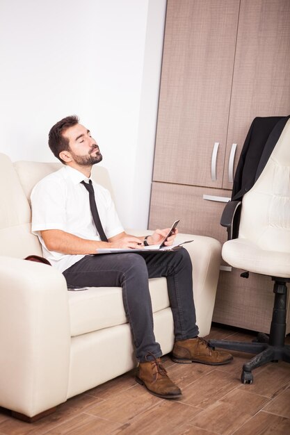 Hombre de negocios que trabaja en la oficina en el sofá poniendo largas horas de trabajo. Empresario en entorno profesional