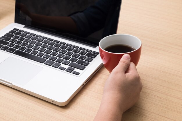 Hombre de negocios que trabaja con ordenador portátil y beber café con copyspace en la oficina.