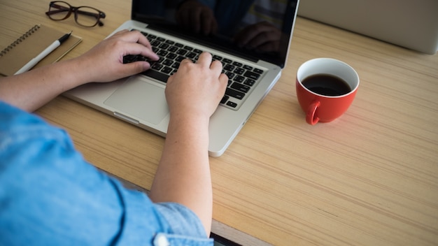 Hombre de negocios que trabaja con ordenador portátil y beber café con copyspace en la oficina.