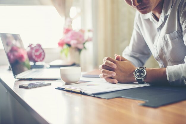 El hombre de negocios que trabaja en su escritorio con una taza de café en la oficina.