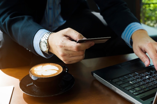 Hombre de negocios que usa la tarjeta de crédito para comprar artículos en línea en la cafetería