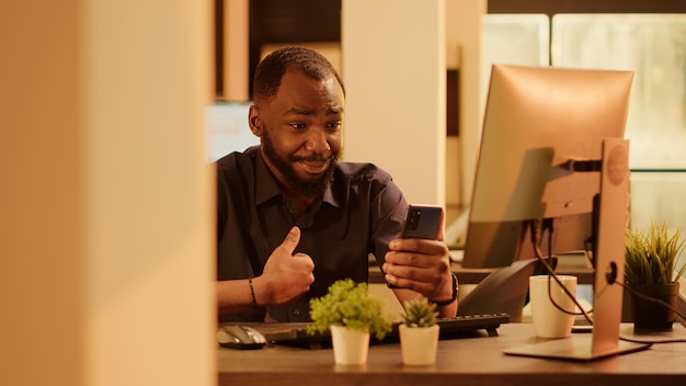 Hombre de negocios que usa un teléfono inteligente para hablar en una videoconferencia en línea, asiste a una reunión de videollamadas en Internet con compañeros de trabajo en una cámara web. Charlando en la red de teleconferencias remotas durante la puesta de sol.