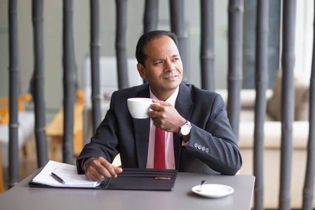 Hombre de negocios reflexivo que bebe el café en el café