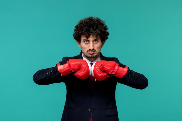 Foto gratuita hombre de negocios rizado lindo chico guapo en traje negro y corbata roja listo para pelear en guantes de boxeo rojos