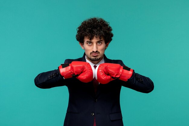 Hombre de negocios rizado lindo chico guapo en traje negro y corbata roja listo para pelear en guantes de boxeo rojos