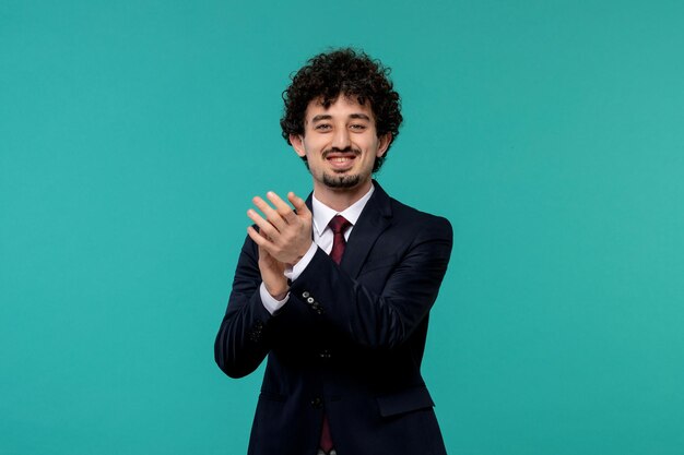 Hombre de negocios rizado lindo chico guapo en traje negro sonriendo y aplaudiendo