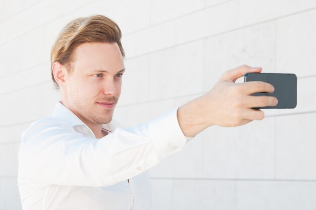 Hombre de negocios seguro de sí mismo tomando selfie foto al aire libre