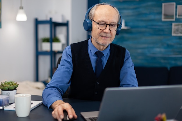 Hombre de negocios senior escuchando música usando audífonos