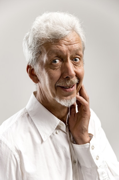 Foto gratuita hombre de negocios senior feliz de pie y sonriendo aislado en estudio gris