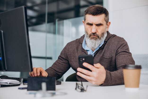 Hombre de negocios senior guapo trabajando en la computadora en la oficina