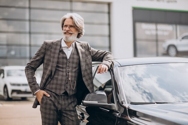 Hombre de negocios senior en una sala de exposición de coches eligiendo un coche