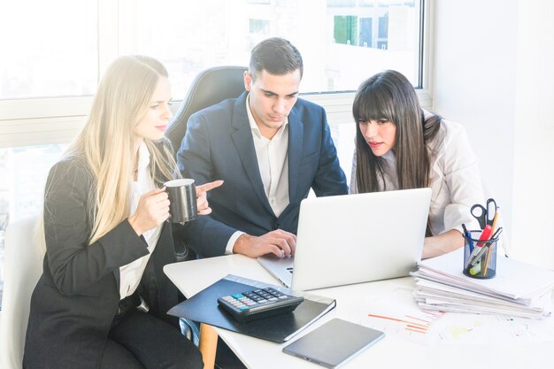 Hombre de negocios sentado con dos mujeres que trabajan en la oficina