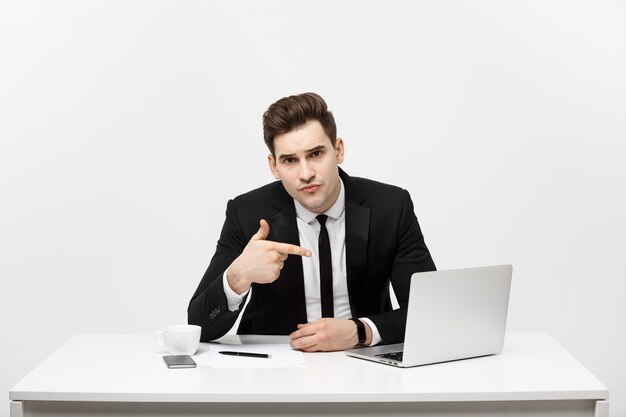 Hombre de negocios sentado en el escritorio señalar con el dedo en la pantalla de la computadora portátil aislada mirada de hombre de negocios joven guapo ...