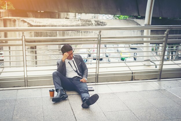 Hombre de negocios sentado en el suelo estresado.