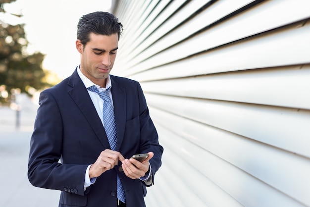 Hombre de negocios serio escribiendo en un teléfono