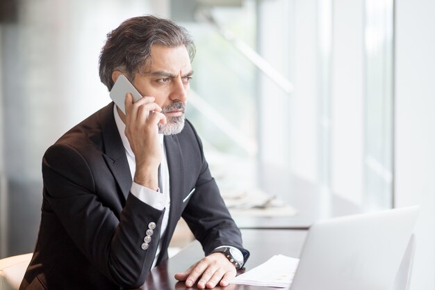 Hombre de negocios serio hablando por teléfono en el escritorio