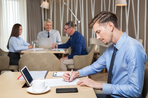 Hombre de negocios serio joven y el equipo que trabaja en café