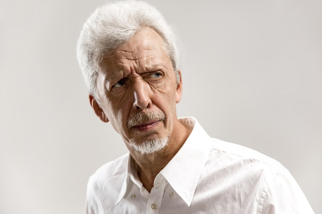 Hombre de negocios serio de pie, aislado en la pared gris. Retrato masculino de medio cuerpo. Las emociones humanas, el concepto de expresión facial.