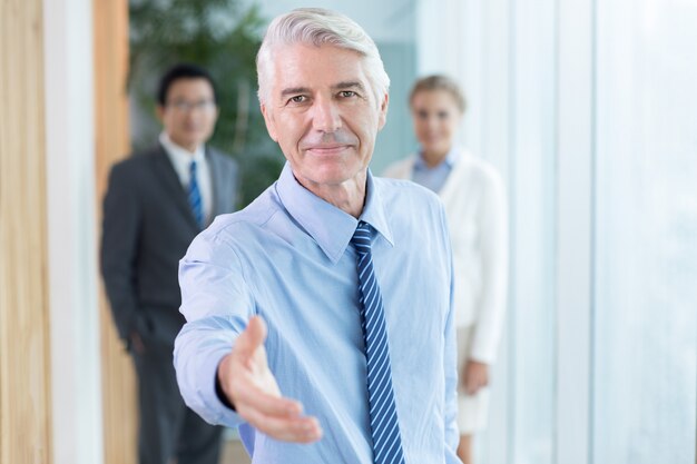 Hombre de negocios serio que se extiende la mano para apretón de manos