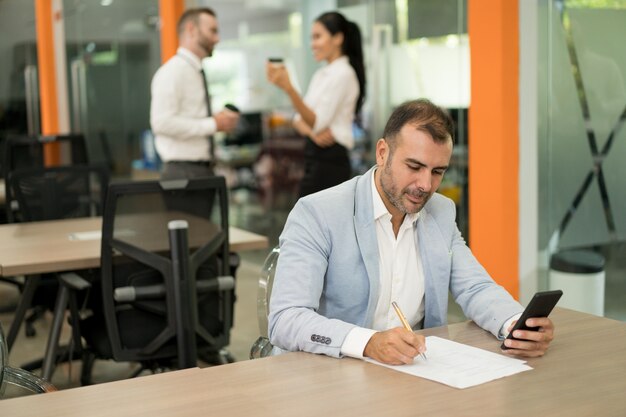 Hombre de negocios serio que trabaja, usando teléfono inteligente