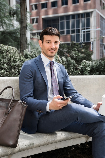 Hombre de negocios con smartphone y bebida