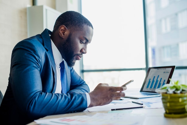 Foto gratuita hombre de negocios con smartphone en su oficina