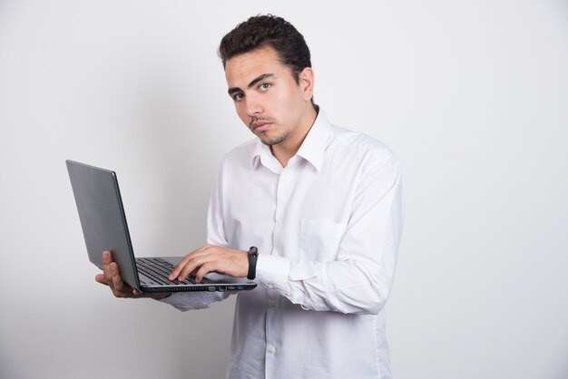 Hombre de negocios solemne usando laptop sobre fondo blanco.