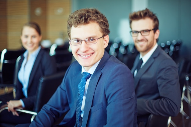 Hombre de negocios sonriendo con trabajadores de fondo