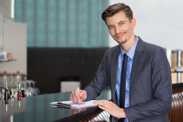 Hombre de negocios sonriente adulto Escritura en el Café Contador