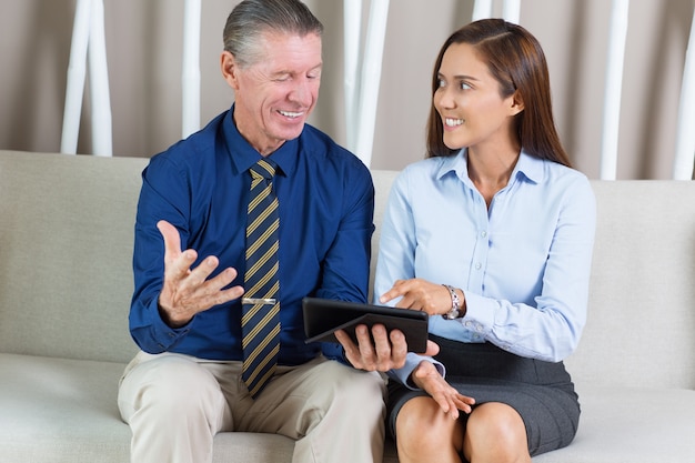 El hombre de negocios sonriente y compañera de trabajo en el sofá