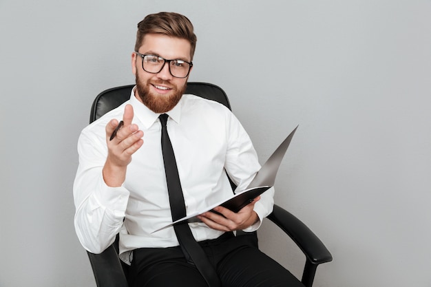 Hombre de negocios sonriente feliz en lentes que sostiene la carpeta