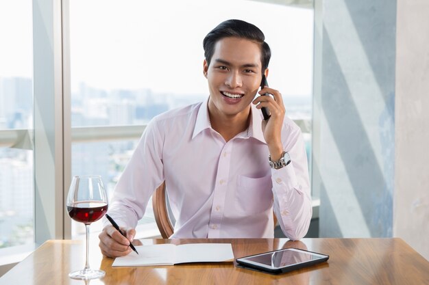 Hombre de negocios sonriente que habla en el teléfono inteligente de Asia