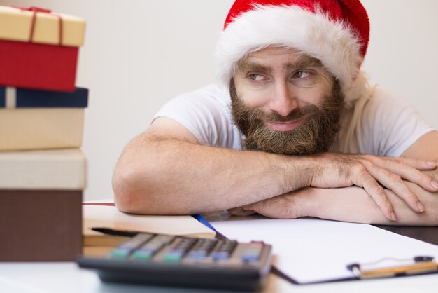 Hombre de negocios sonriente que lleva el sombrero de Papá Noel y que se relaja